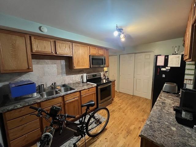 kitchen featuring appliances with stainless steel finishes, sink, decorative backsplash, and dark stone counters