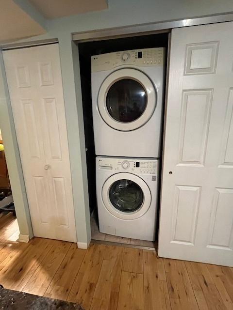 washroom featuring stacked washer and dryer and light hardwood / wood-style flooring