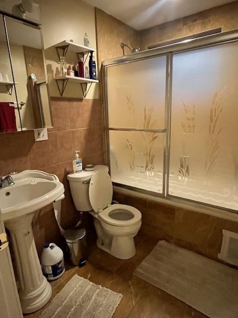 bathroom with tile walls, sink, and toilet