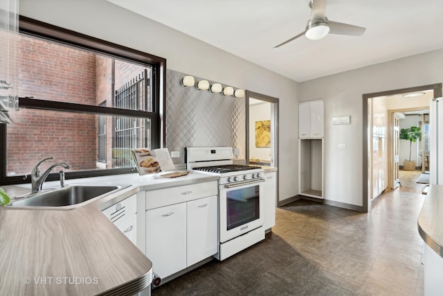 kitchen featuring white gas range, sink, white cabinets, and ceiling fan