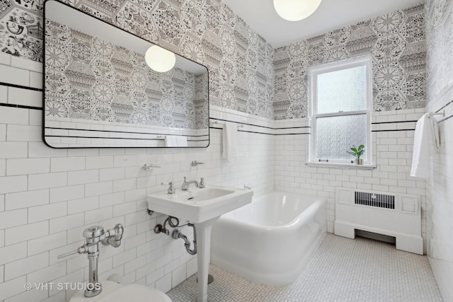 bathroom with radiator, sink, tile walls, tile patterned floors, and a tub