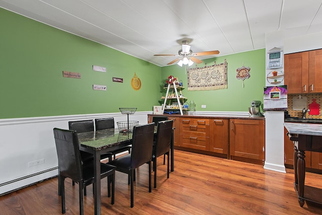 dining room with ceiling fan, a baseboard radiator, and wood-type flooring