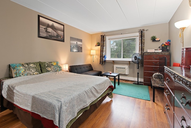 bedroom with hardwood / wood-style floors and a wall mounted AC