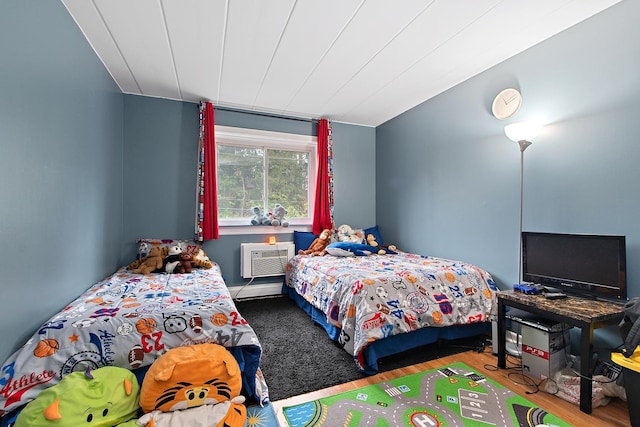 bedroom with hardwood / wood-style flooring, a wall mounted AC, and vaulted ceiling