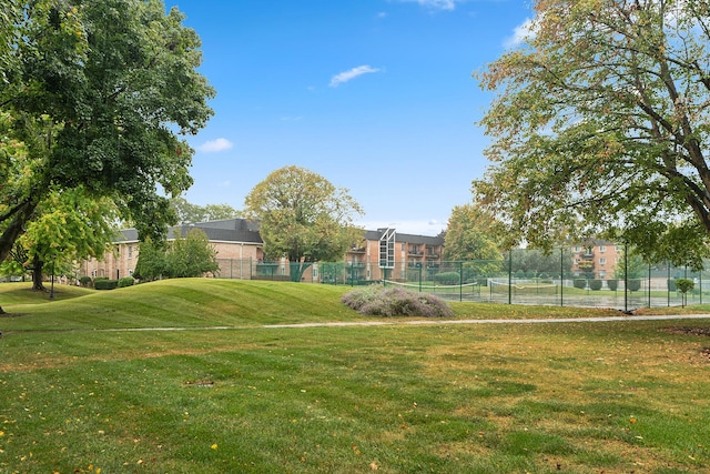 view of property's community with a yard and tennis court