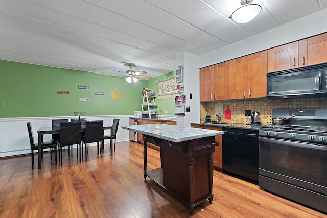 kitchen featuring a kitchen island, sink, decorative backsplash, black appliances, and light hardwood / wood-style flooring