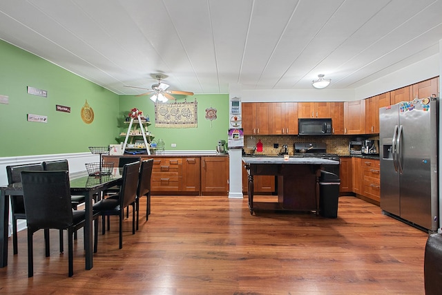 kitchen with decorative backsplash, dark hardwood / wood-style floors, a kitchen island, and black appliances