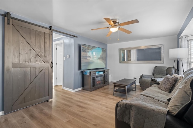 living room featuring ceiling fan, a barn door, and light hardwood / wood-style floors