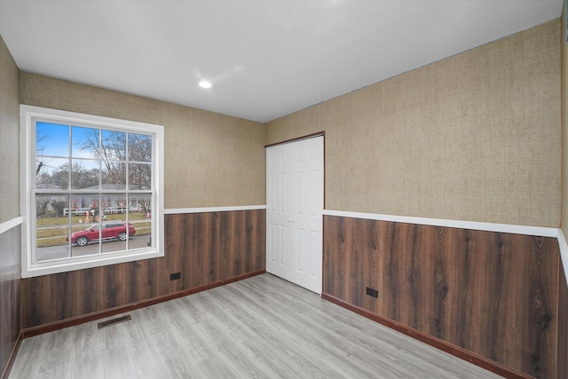 spare room featuring light hardwood / wood-style floors and wood walls