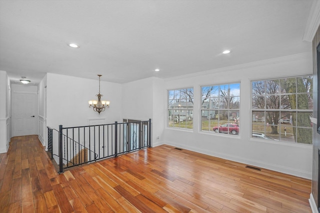 empty room with an inviting chandelier, ornamental molding, and light wood-type flooring