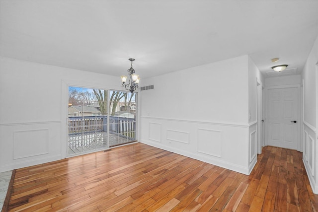 unfurnished dining area with a notable chandelier and wood-type flooring