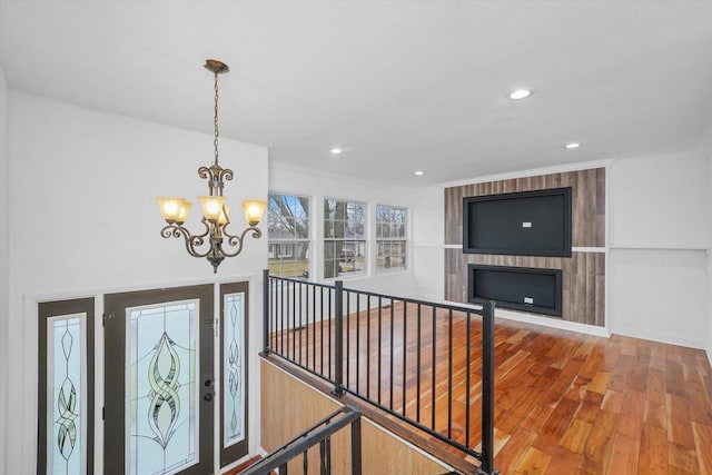 corridor with hardwood / wood-style flooring, crown molding, and an inviting chandelier