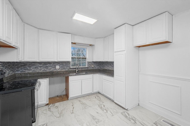 kitchen featuring tasteful backsplash, white cabinetry, black electric range oven, and sink