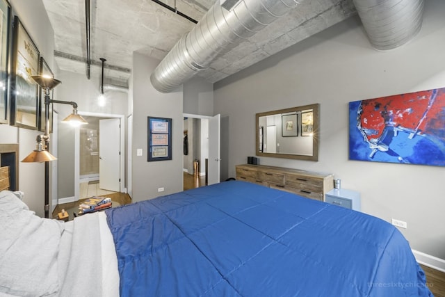 bedroom featuring ensuite bath and wood-type flooring