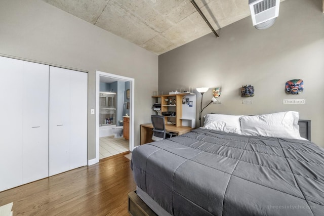 bedroom with connected bathroom, wood-type flooring, and a closet