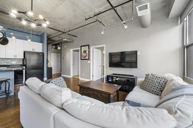 living room featuring rail lighting, dark hardwood / wood-style floors, and a high ceiling