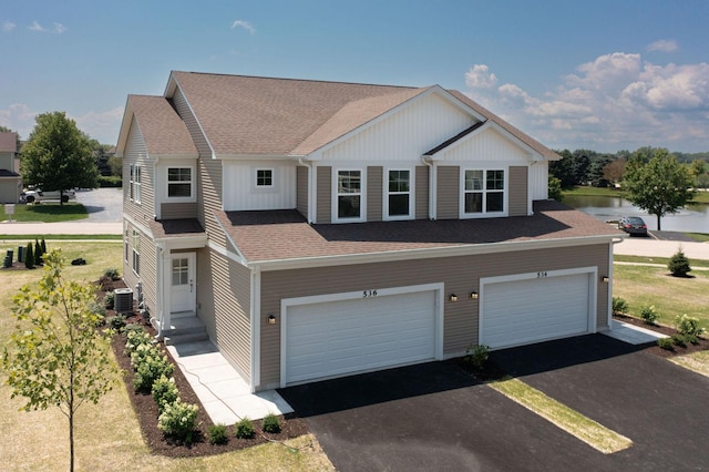 view of front of house with a garage, central air condition unit, and a water view