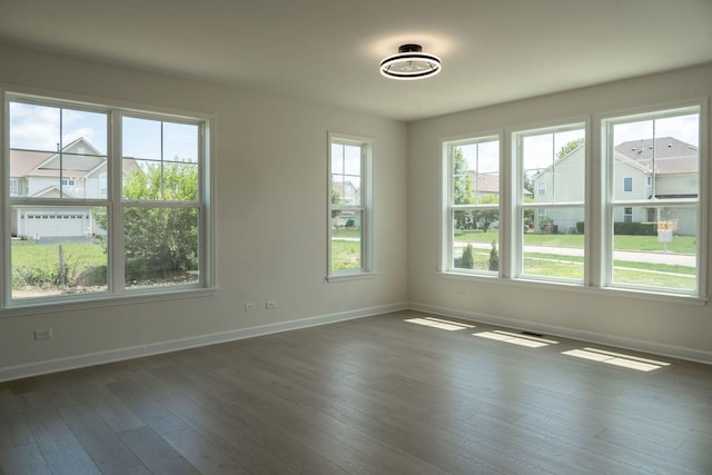 spare room with dark wood-type flooring and plenty of natural light