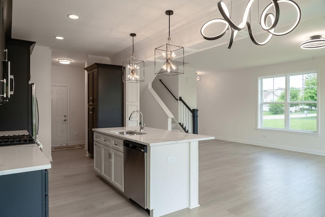 kitchen with pendant lighting, sink, an island with sink, stainless steel dishwasher, and light wood-type flooring