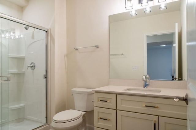 bathroom featuring vanity, a shower with door, and toilet