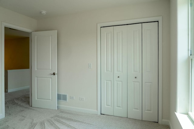 unfurnished bedroom featuring light carpet and a closet