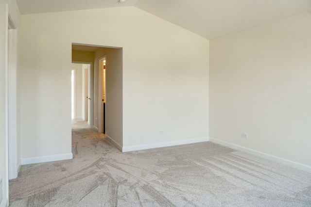 spare room featuring light colored carpet and lofted ceiling