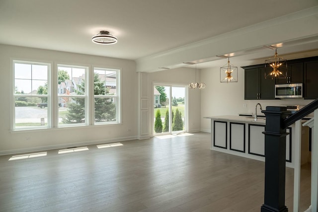 kitchen with decorative light fixtures, sink, and light wood-type flooring