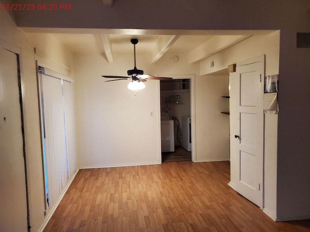 unfurnished bedroom featuring beam ceiling, washing machine and dryer, and light hardwood / wood-style flooring