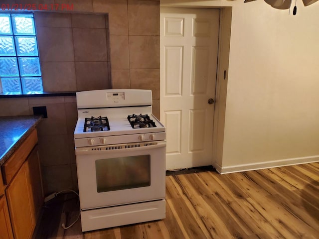 kitchen with white range with gas cooktop, ceiling fan, and light hardwood / wood-style flooring