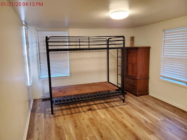 unfurnished bedroom featuring multiple windows and light wood-type flooring