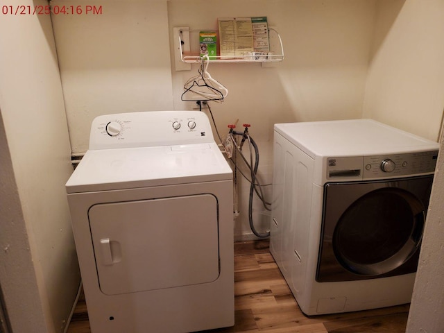 clothes washing area with washer and clothes dryer and light hardwood / wood-style floors