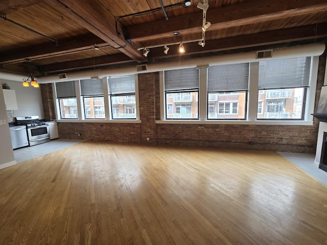 unfurnished living room featuring brick wall, light wood-type flooring, wooden ceiling, beamed ceiling, and a healthy amount of sunlight