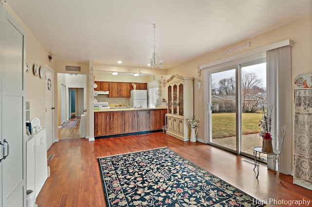 kitchen featuring range, tasteful backsplash, dark hardwood / wood-style flooring, kitchen peninsula, and white fridge