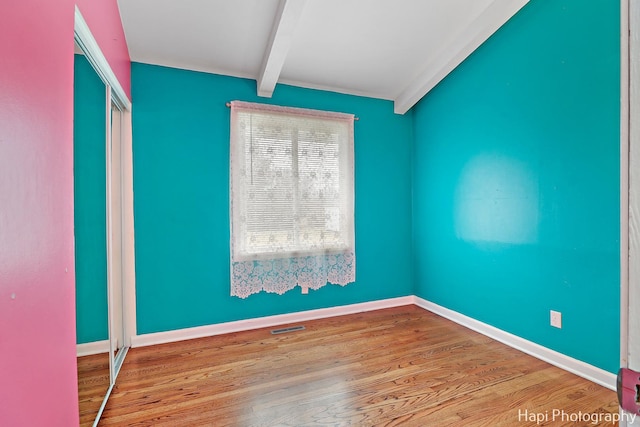 unfurnished room with beam ceiling and light hardwood / wood-style floors