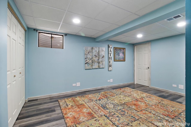 basement with a drop ceiling and dark hardwood / wood-style floors