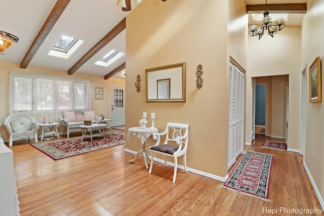 living room with beam ceiling, high vaulted ceiling, light wood-type flooring, and a skylight