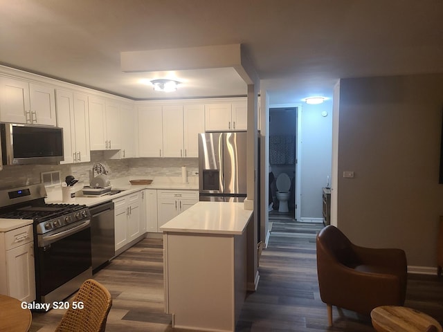 kitchen with white cabinetry, a center island, dark hardwood / wood-style floors, stainless steel appliances, and backsplash