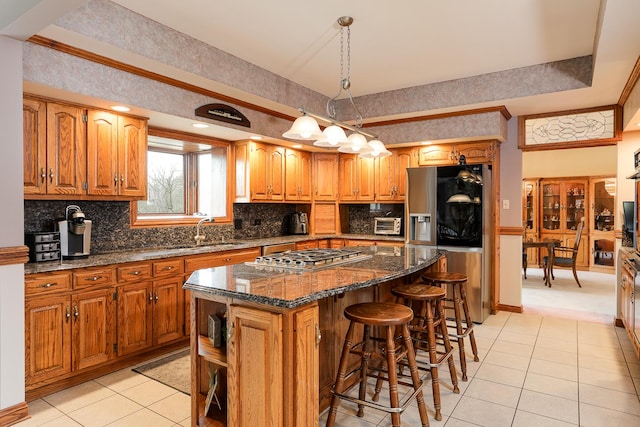 kitchen with stainless steel appliances, a center island, decorative light fixtures, sink, and light tile patterned floors