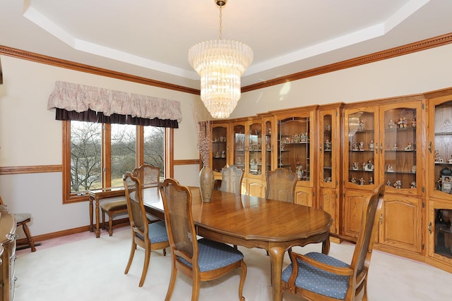 carpeted dining area with crown molding, a notable chandelier, and a raised ceiling