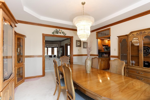 dining room with light carpet, crown molding, an inviting chandelier, and a raised ceiling