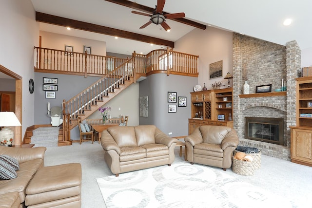 carpeted living room with a fireplace, beamed ceiling, a high ceiling, and ceiling fan