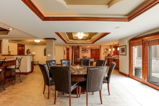 dining area featuring a tray ceiling, ornamental molding, light tile patterned floors, and decorative columns