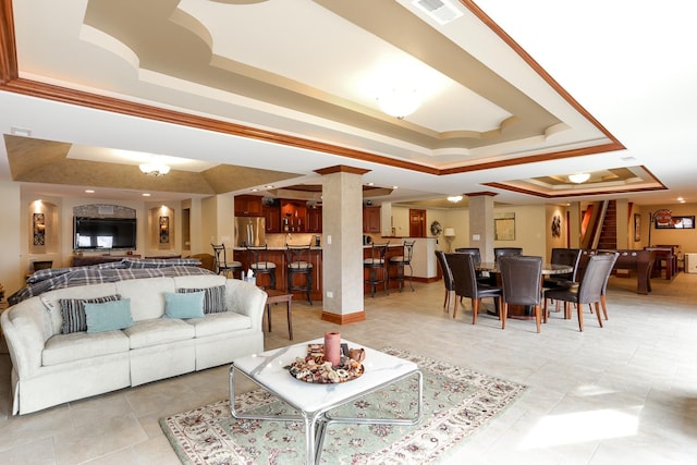 tiled living room with ornate columns, crown molding, and a raised ceiling