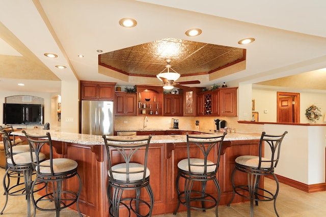 kitchen featuring a raised ceiling, a breakfast bar, and stainless steel fridge