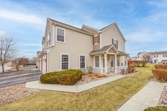 view of front facade with aphalt driveway, covered porch, a front lawn, and a garage