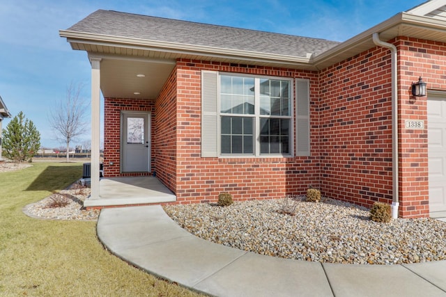 view of exterior entry featuring a garage and a lawn