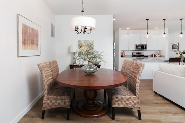 dining space with an inviting chandelier and light hardwood / wood-style flooring