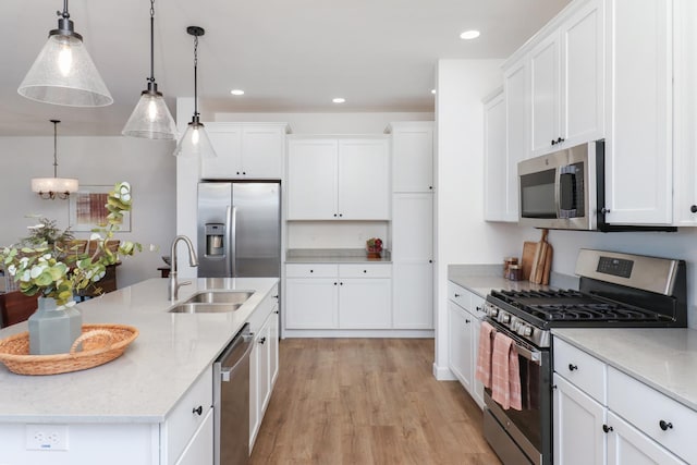 kitchen featuring sink, stainless steel appliances, hanging light fixtures, and light stone countertops