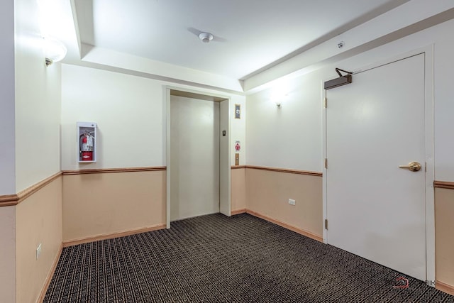 carpeted empty room featuring elevator