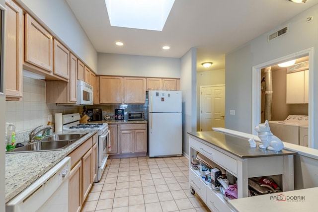 kitchen featuring sink, white appliances, a skylight, independent washer and dryer, and decorative backsplash